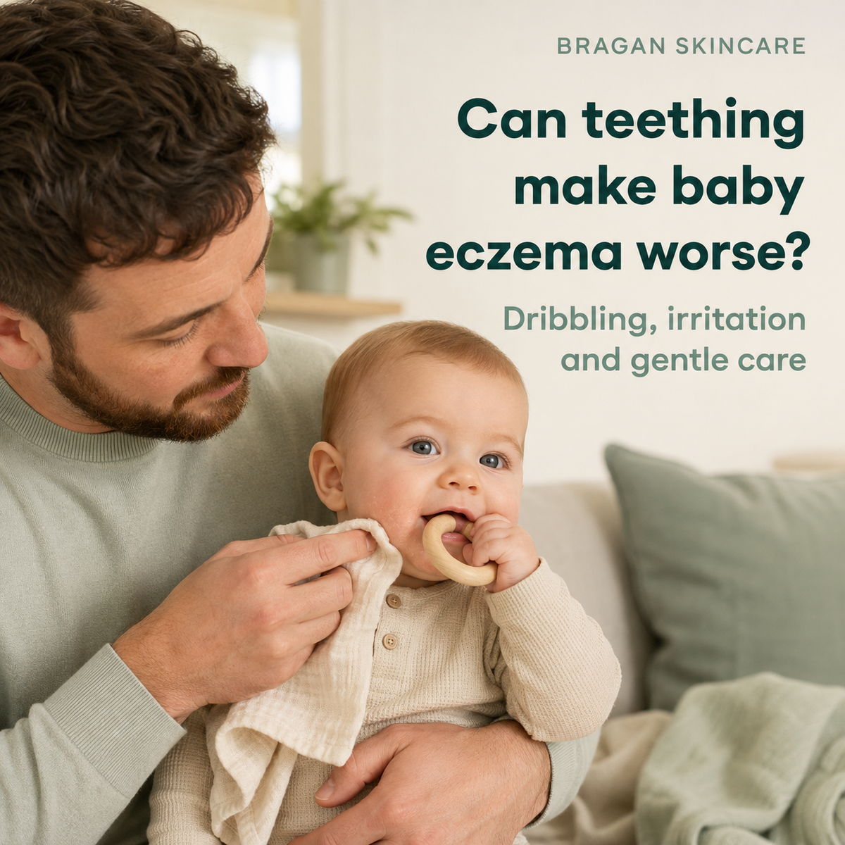 Father gently wiping dribble from his teething baby’s eczema-prone chin while the baby chews a wooden teething ring.