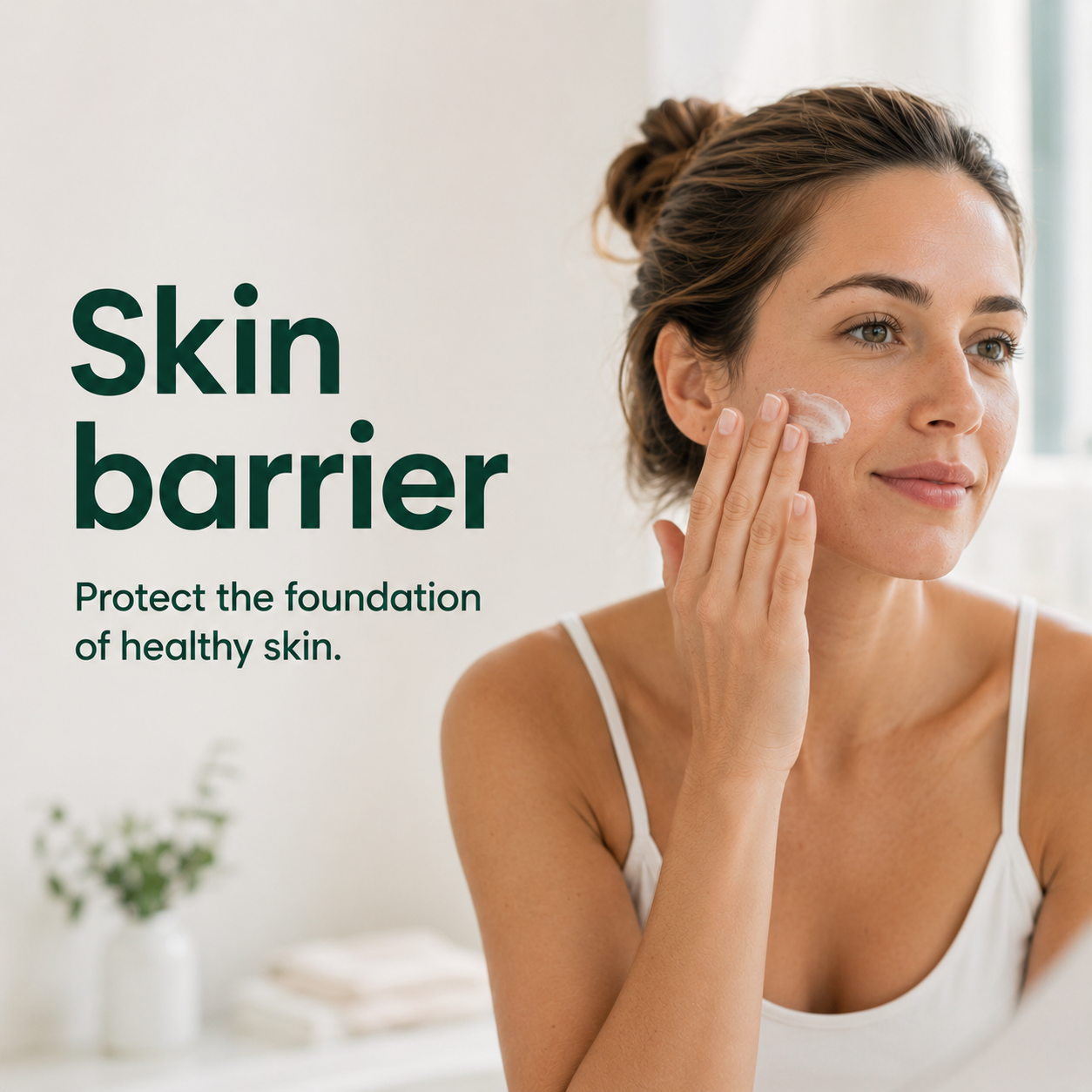Woman applying moisturiser to support her skin barrier in a bright bathroom, illustrating a gentle daily skincare routine for healthy skin.