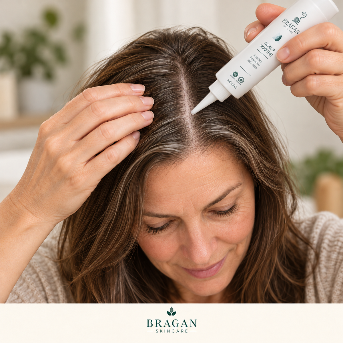 Illustrative image of a woman applying Bragan Scalp Soothe directly to her scalp along a hair parting using the precision nozzle.