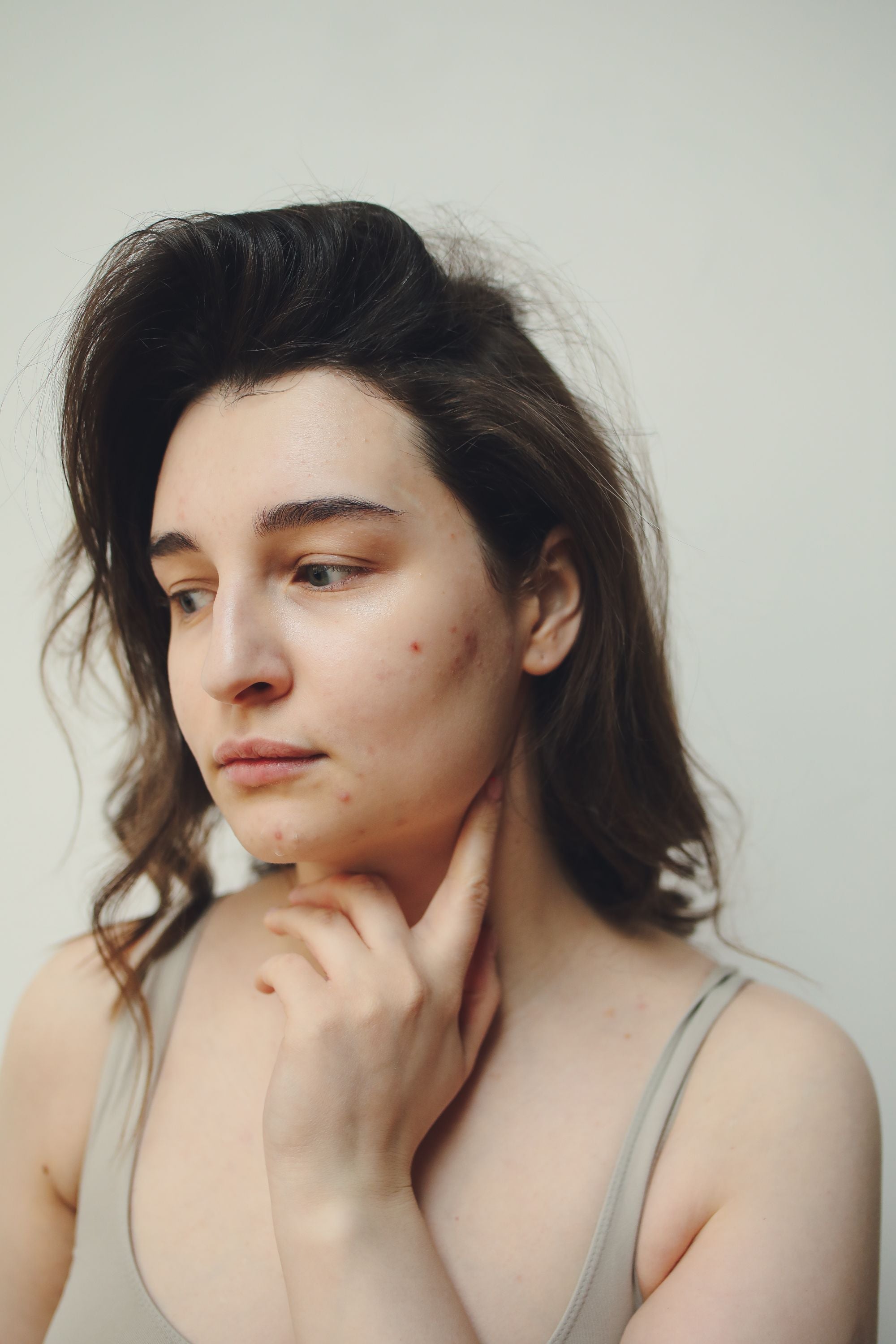 Person noticing a recurring acne breakout while looking in a bathroom mirror.
