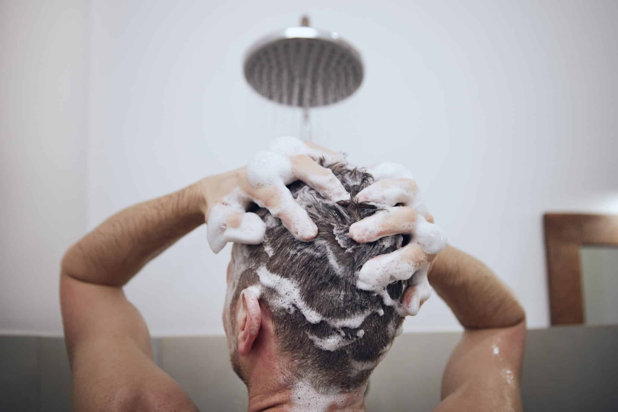 A man washes his hair with shampoo.