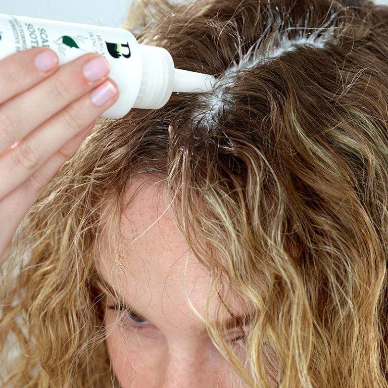 Woman applying Scalp Soothe to middle parting