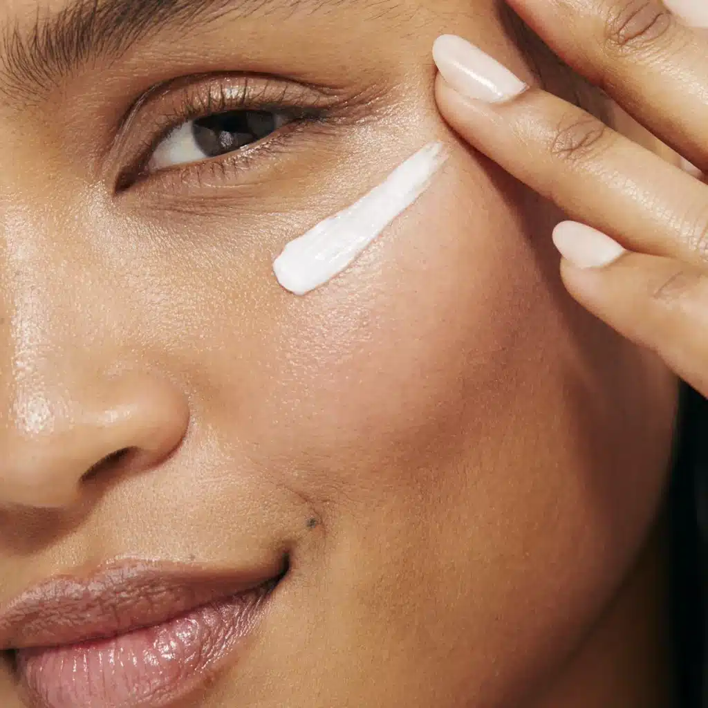 a lady applying cream to her face.